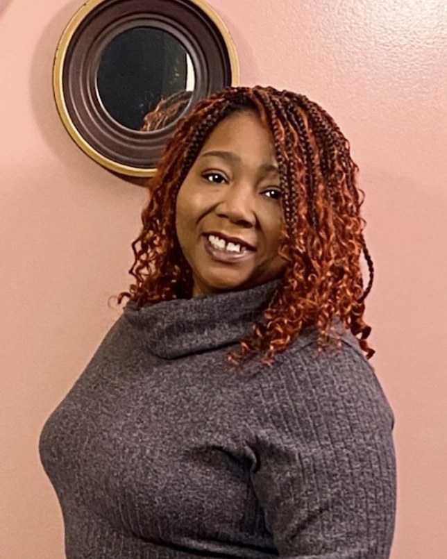 Shanita Wade, MA, LPC, smiling, wearing a gray turtleneck sweater in front of a soft pink wall